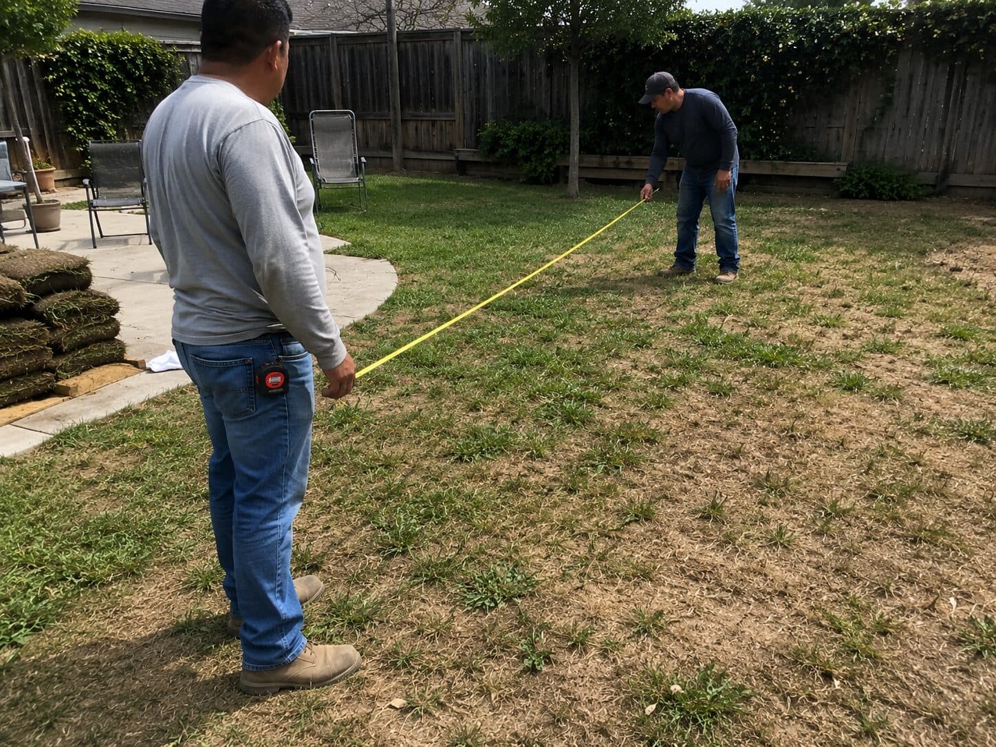 Workers measuring a backyard before a sod installation